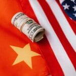 From above of roll of dollar bills tied with rubber band on bright American flag with stars and stripes symbolizing unity and peace